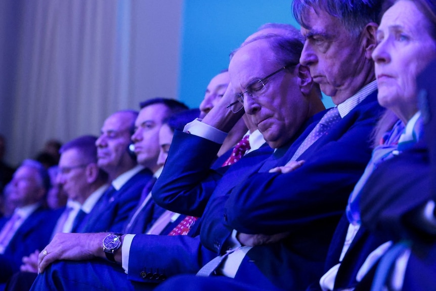 A line of seated people looking serious.