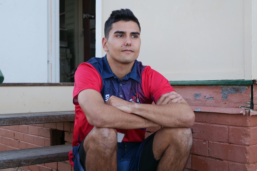 Jarib Branfield sitting on steps with arms crossed looking out into distance.