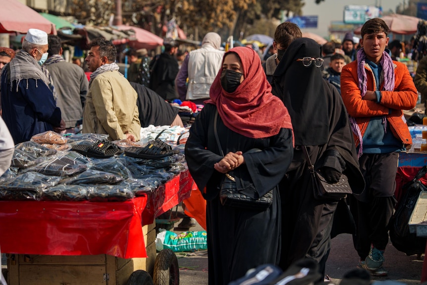 A woman covered from head to toe walks in a market in Kabul.