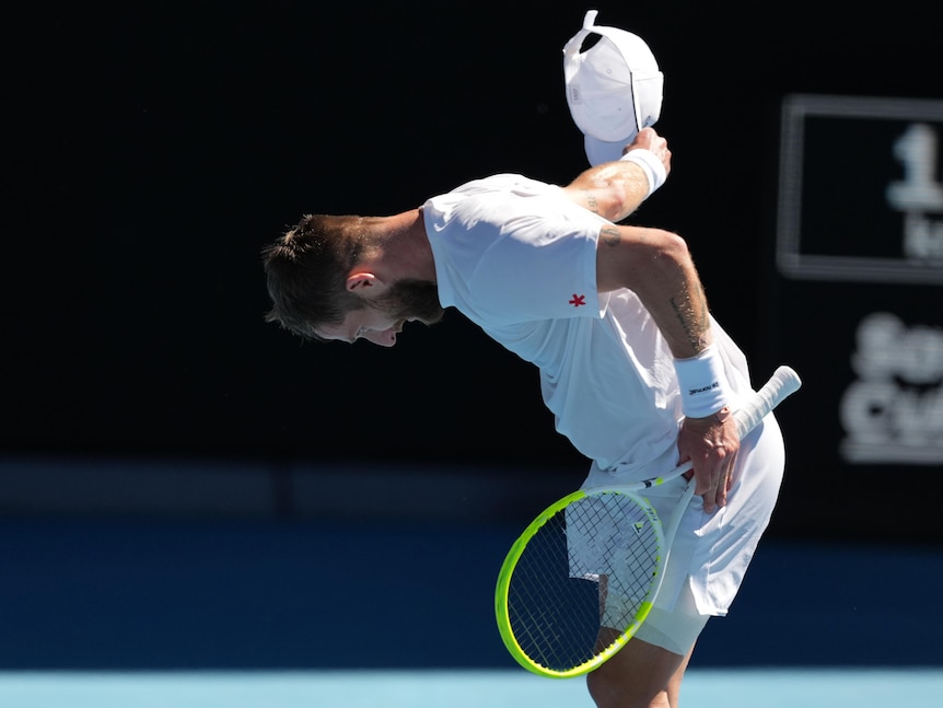 A French tennis player doffs his cap and bows to the crowd at the Australian Open.