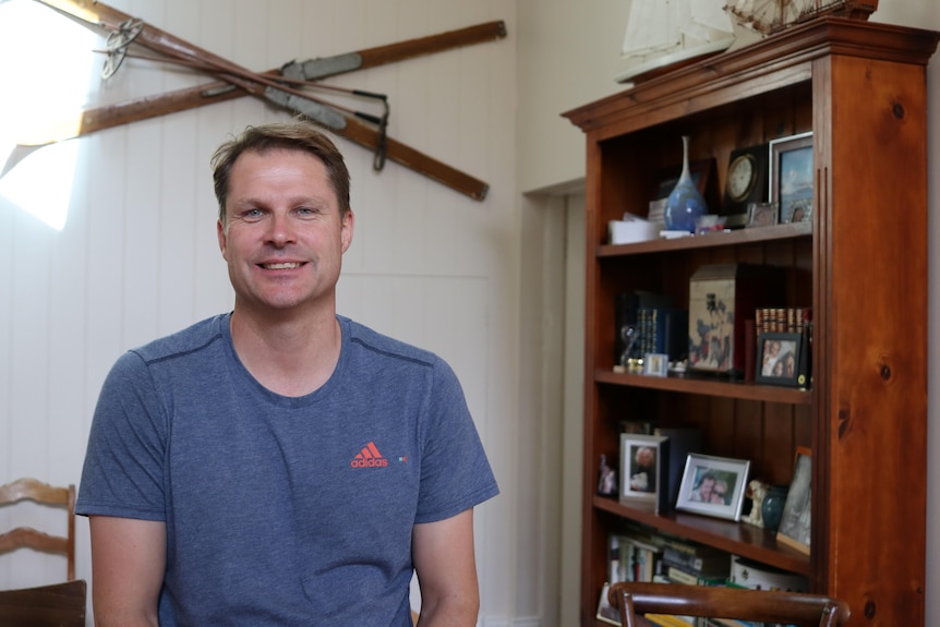 A young man in a t-shirt looks at the camera