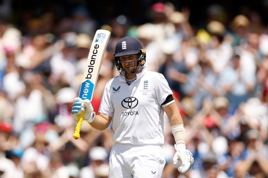 England batter Joe Root holds up his bat to celebrate a half-century.