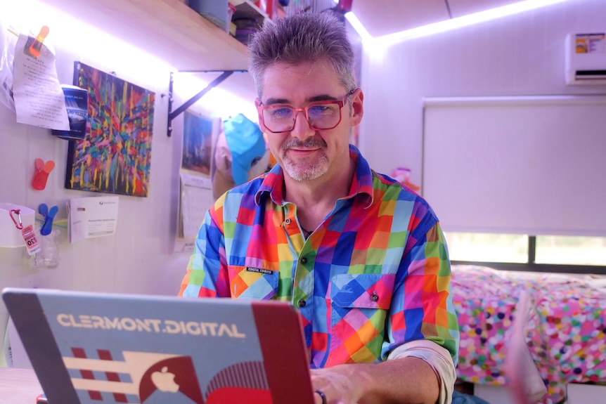 A man in a coulourful shirt works on a computer to create the Gauge weather website.