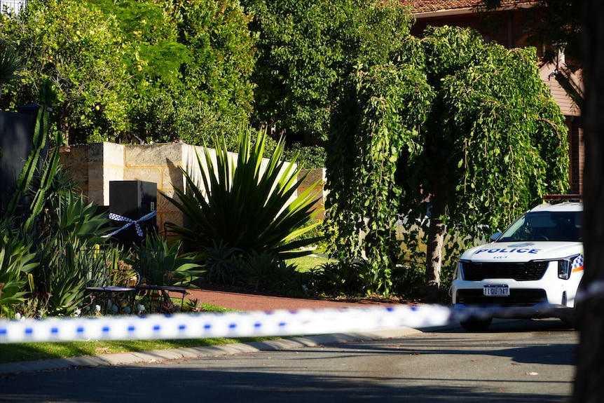 Police tape and a police car parked ouitside a house