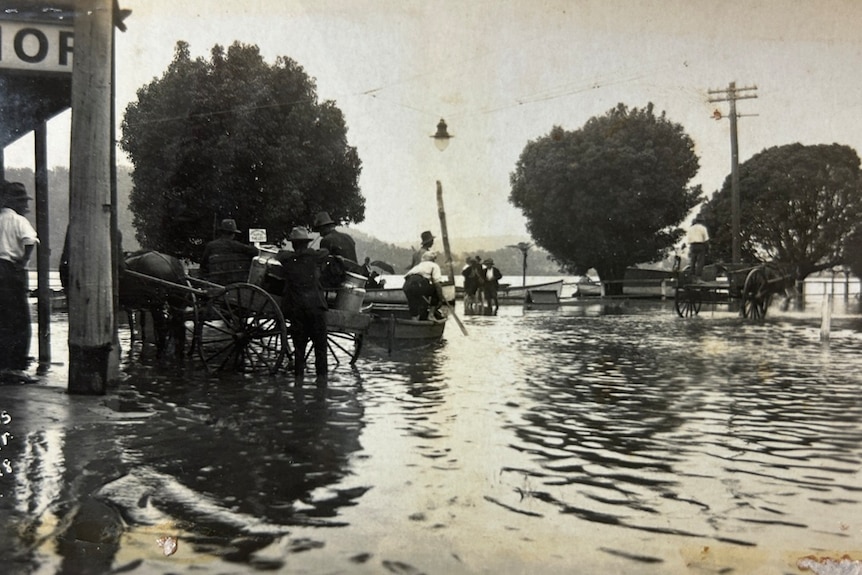 1928  black and white photo of people outside a shop in flood
