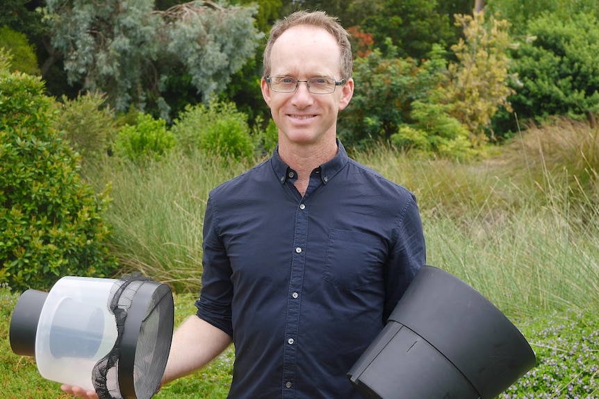 a man smiling holding mosquito nets.