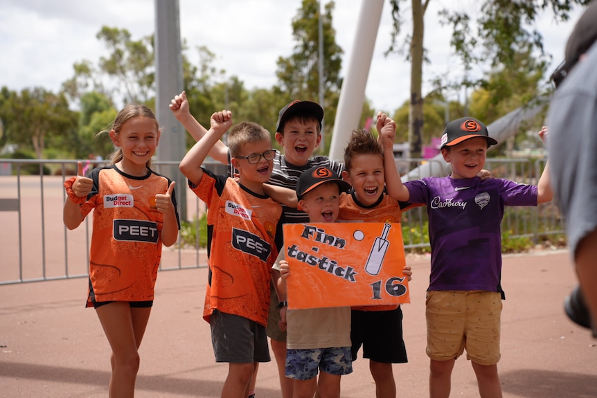 Children dressed in orange holding up a sign that says "Finn Tastic"