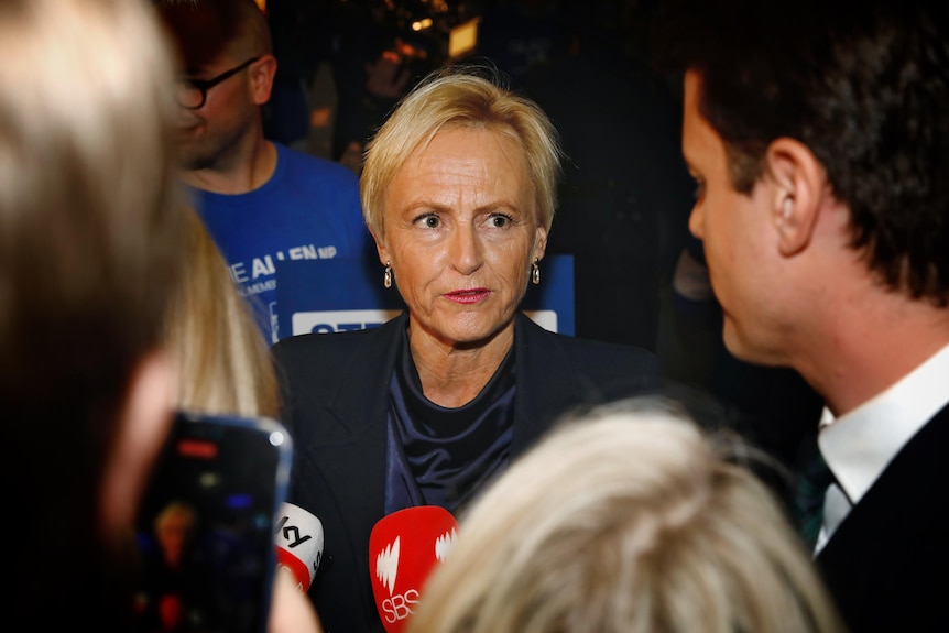 Katie Allen looks at a male reporter who is among a press pack shown standing in front of her at a campaign event