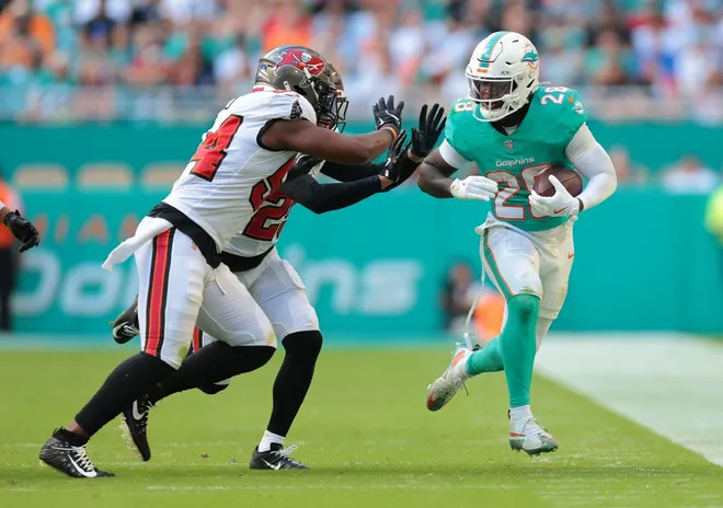 Dec 28, 2025; Miami Gardens, Florida, USA; Miami Dolphins running back De'Von Achane (28) runs for a gain past Tampa Bay Buccaneers cornerback Jacob Parrish (25) and linebacker Lavonte David (54) during the third quarter at Hard Rock Stadium.