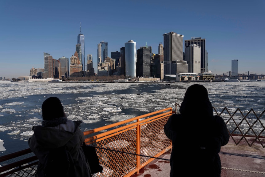A shot of the skyline of New York City seen from a ferry with ice on the harbour.
