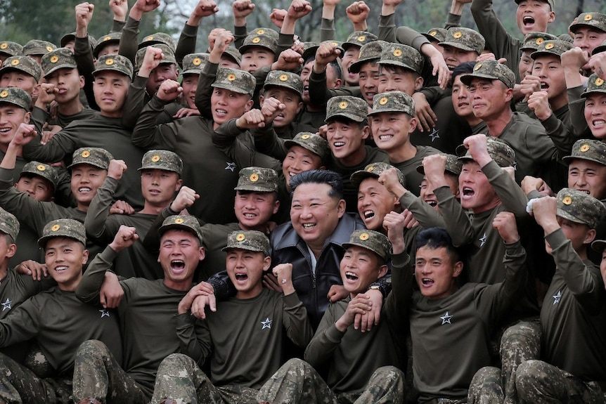 A large crowd of soldiers, surrounding a man. Everyone is smiling.