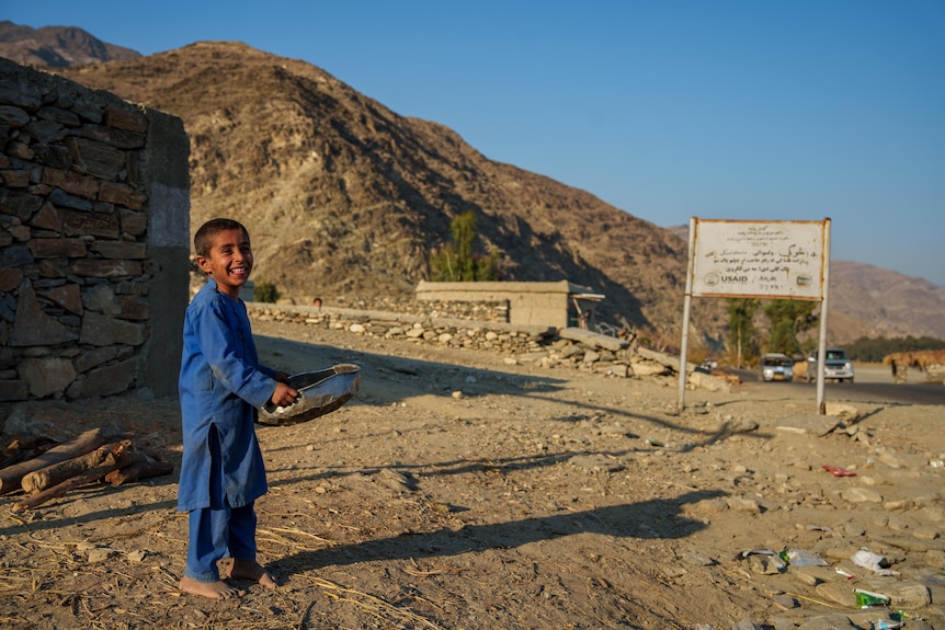 An Afghan boy smiles near a village in Afghanistan.
