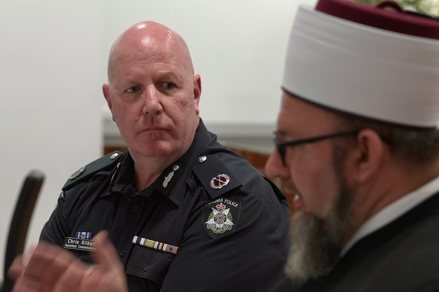 Imam Ismet Purdic sits with a police officer.