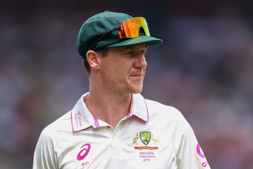 Australia fielder Brendan Doggett stands in the field with his sunglasses on top of his baggy green.