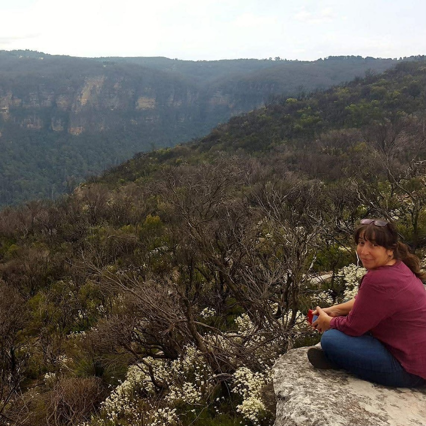 Woman sitting on rock with landscape view.