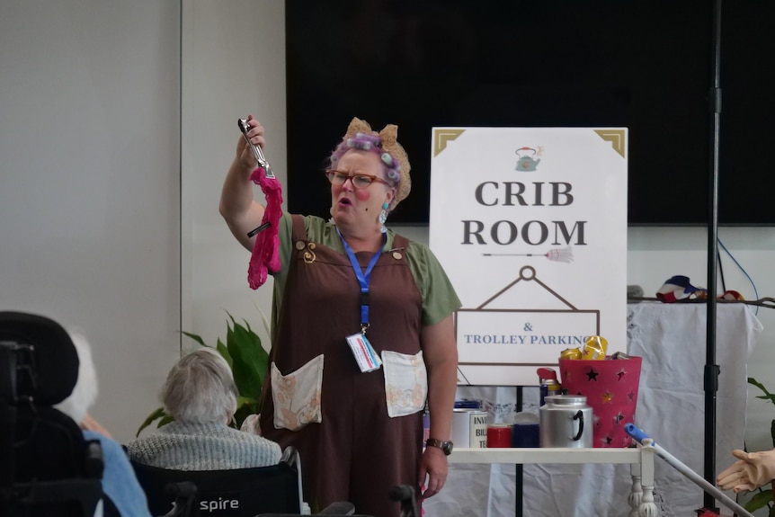 A woman wearing a brown apron acting on stage.