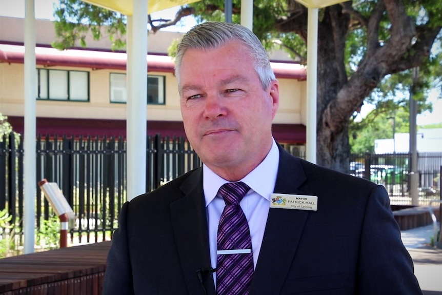 A man in a suit stands in a playground.