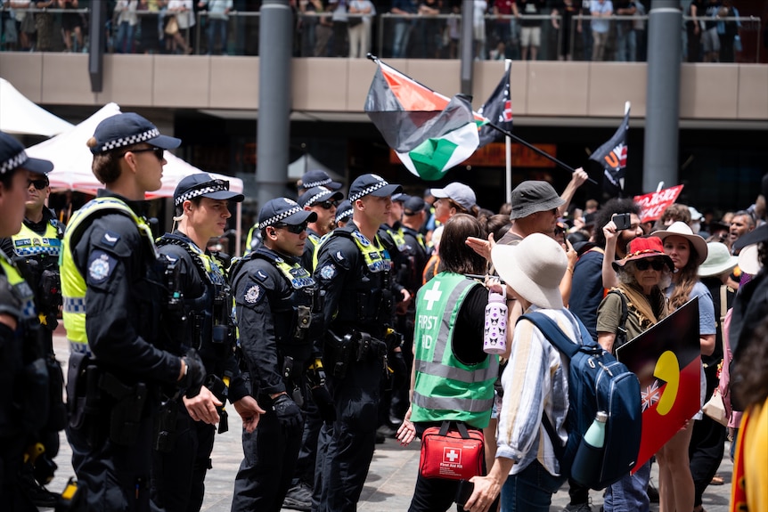 Police and people at a rally form together in a line
