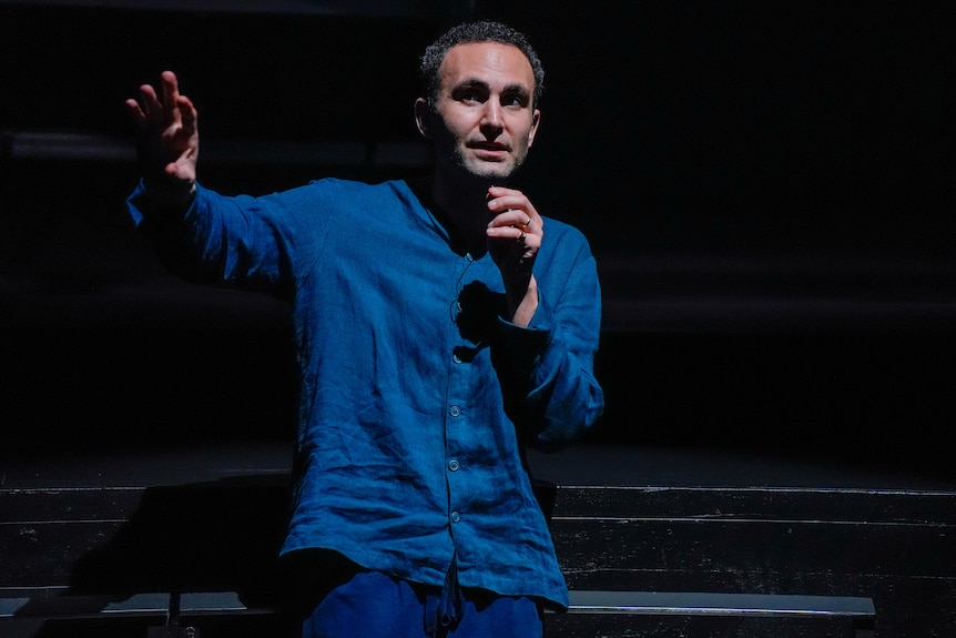 Khalid Abdalla, an Egyptian British man, 45, in blue linen, perches at the edge of the stage, holding a lapel mic to his mouth.
