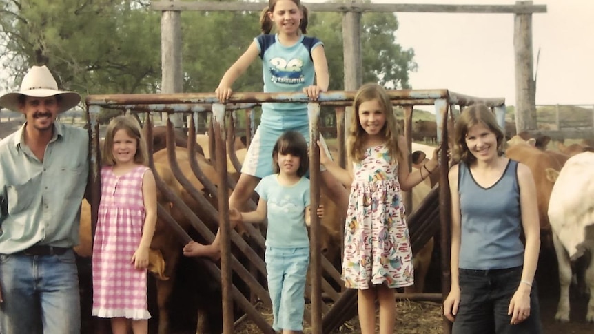 A family posing for a photo in front of a cattle yard.