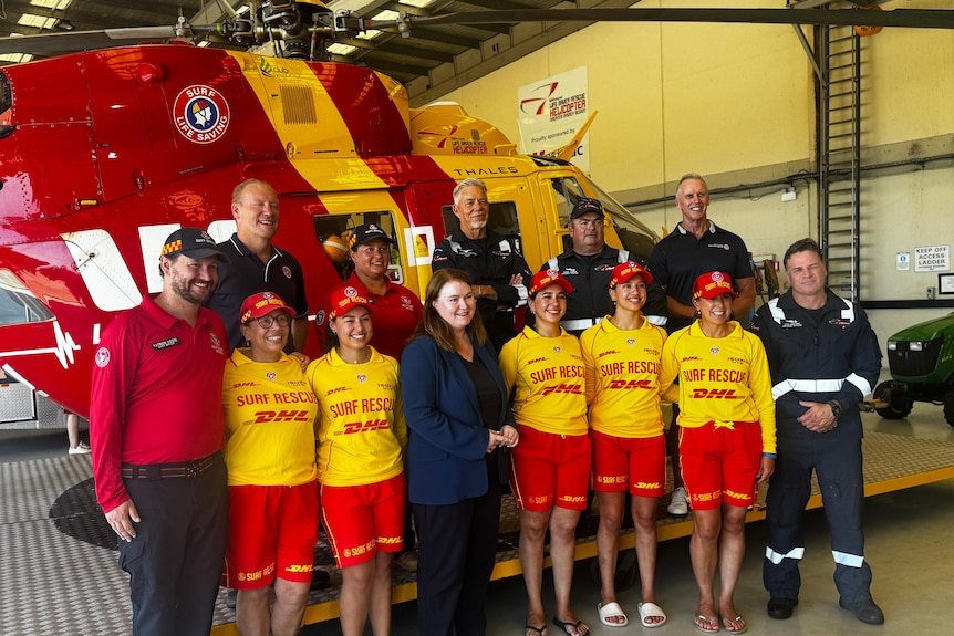 Life savers in front ofwestpac helicopter at an annoouncemnet for more funsing for shark programs in nsw
