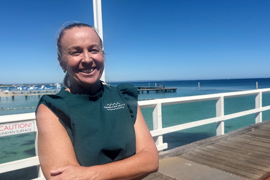 A woman in a green shirt stands on the Busselton jetty 