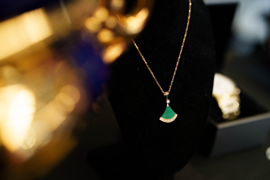 A green fan pendant on a gold chain.