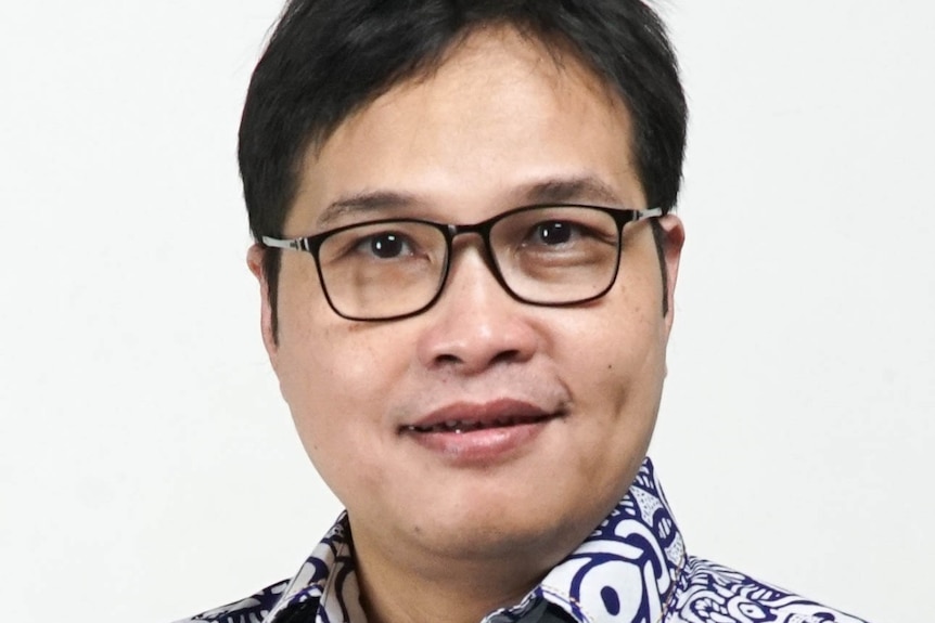 Man wearing glasses smiling to camera.