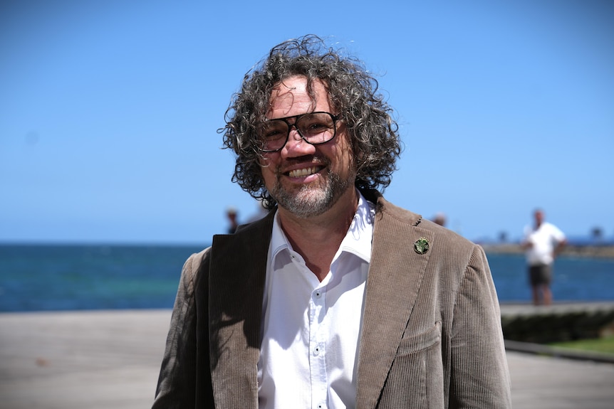 City of Fremantle mayor Ben Lawver smiles with water and blue sky in the background.