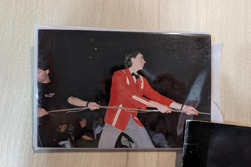 A young man in a red jacket pulls a rope.