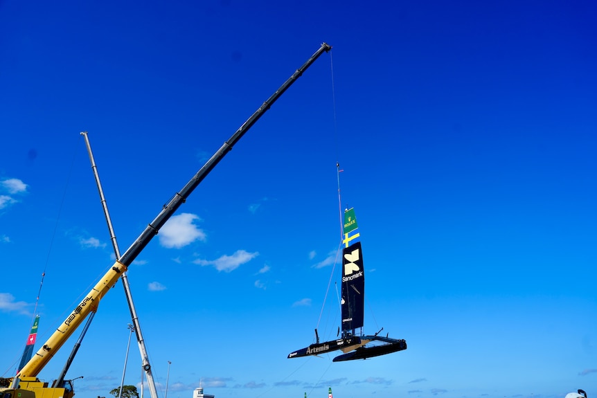 A catamaran being lifted by a crane.