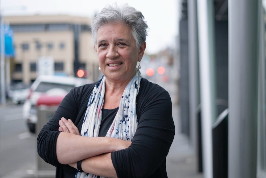 A woman with silver hair crosses her arms 