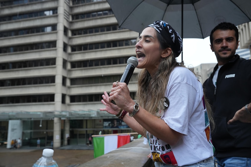 a woman speaks into a microphone during a protest