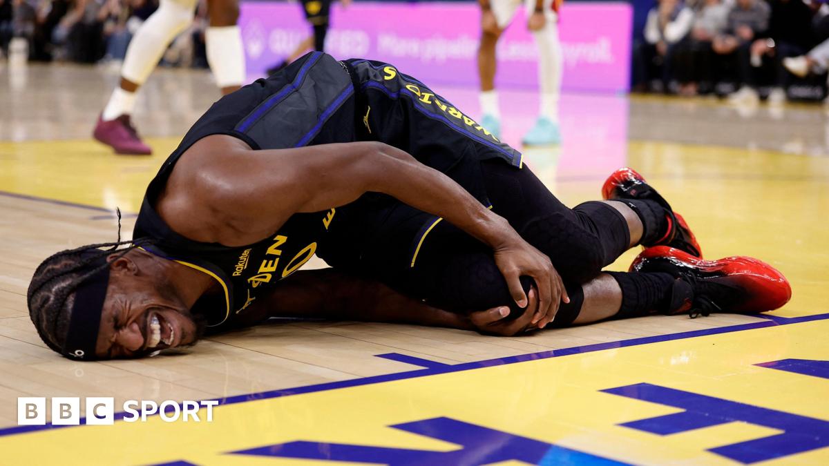Golden State Warriors forward Jimmy Butler lies on the floor in agony, holding his right knee after tearing his ACL
