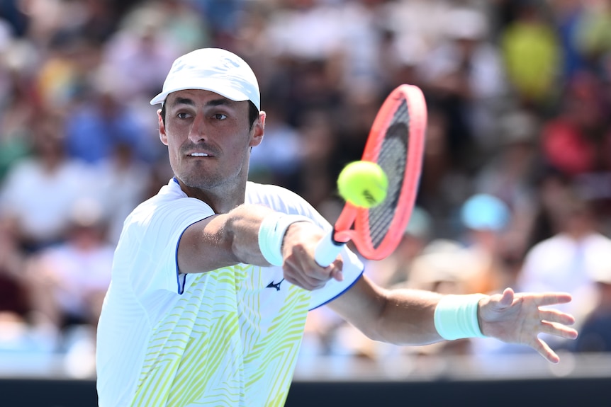Tennis player Bernard Tomic hits a one handed backhand shot.