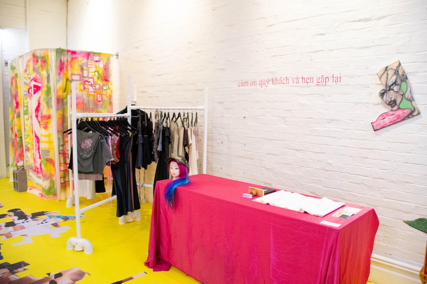 The interior of an independent fashion store's pop-up, showing bright coloured flooring, a clothing rack and a change room. 