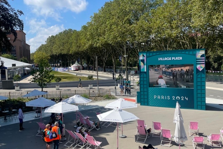 A large screen outside with chairs in front of it.