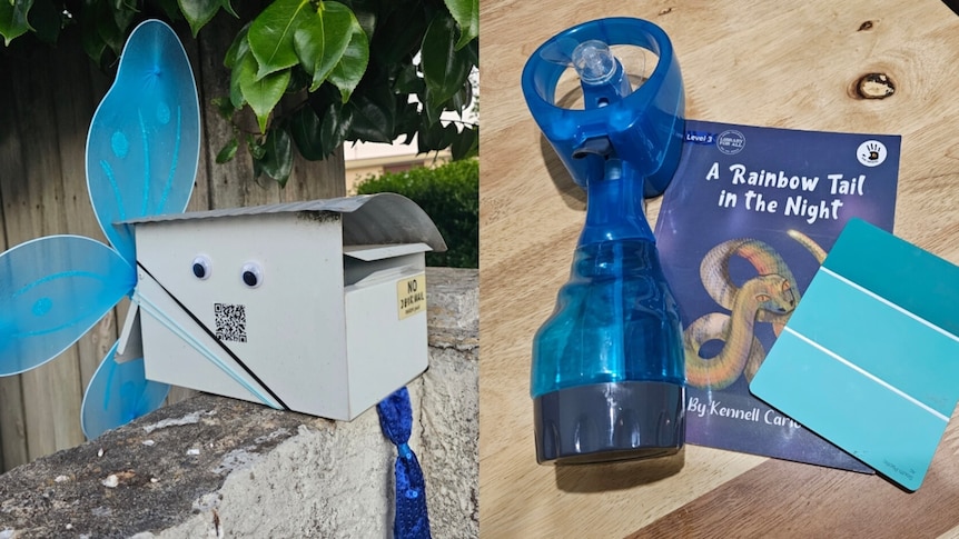 A letterbox with butterfly wings on it along with a blue electric handheld fan, a book and a paint sample card