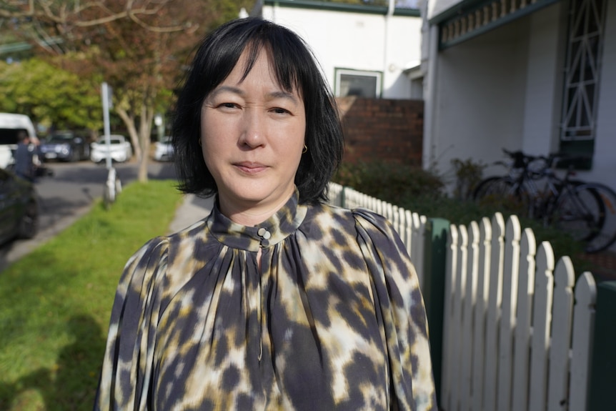 Woman stands on residential street looking into camera.