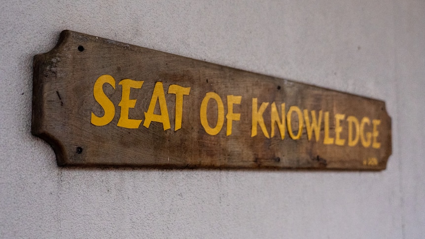 A wooden sihn that says the 'seat of knowledge'.