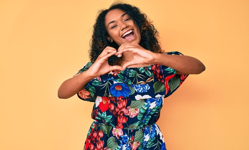 Smiling woman making a heart shape with her hands, representing heart health and cardiovascular wellness.