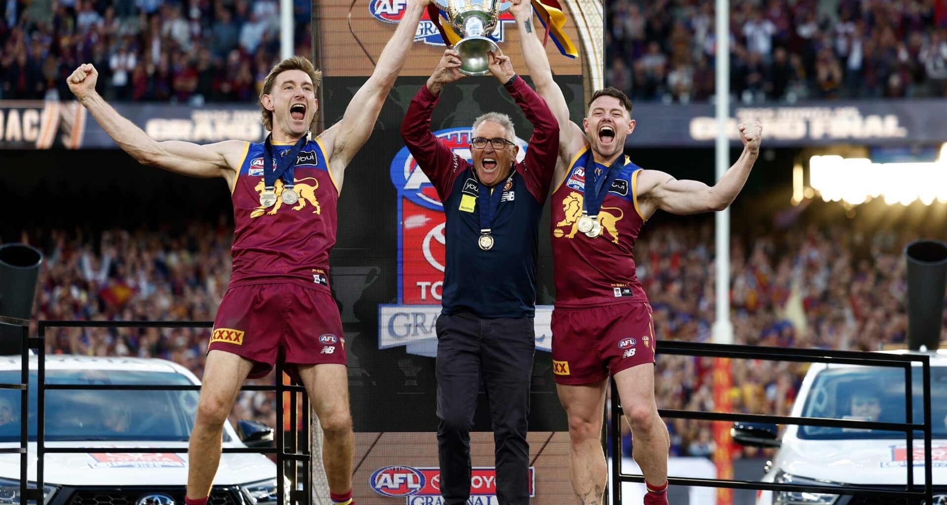 MELBOURNE, AUSTRALIA - SEPTEMBER 27: Harris Andrews of the Lions, Chris Fagan, Senior Coach of the Lions and Lachie Neale of the Lions celebrate with the Premiership Cup on the dais during the AFL Grand Final match between the Geelong Cats and the Brisbane Lions at the Melbourne Cricket Ground on September 27, 2025 in Melbourne, Australia. (Photo by Michael Willson/AFL Photos via Getty Images)
