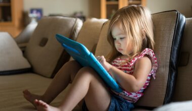 Young girl sitting at home on settee and using a child