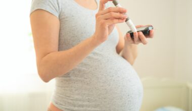 Pregnant woman using a blood glucose meter. Close-up of hands holding a glucometer and test strip.