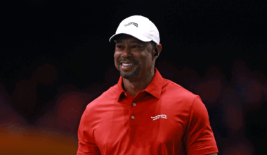 Tiger Woods smiles while wearing a white Sun Day Red cap and a red Sun Day Red polo during a TGL match in 2025