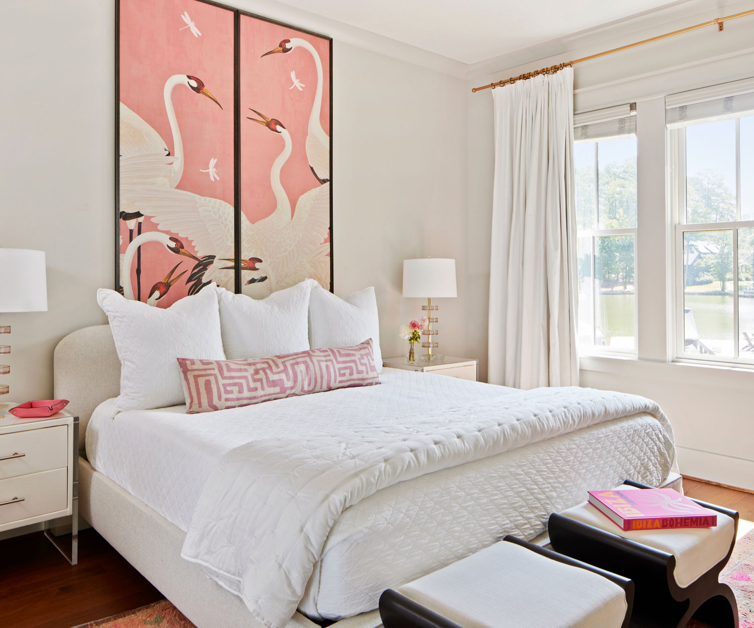 A bedroom with a white color scheme, and pink artwork above the bed.