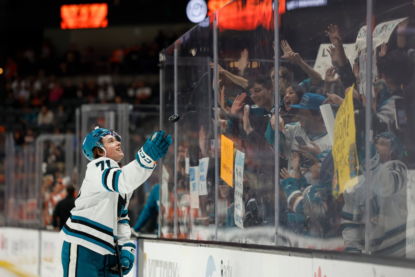 Macklin Celebrini throws a puck to fans.