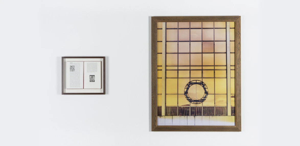 Framed artwork and a framed document on a white wall, featuring grid patterns and a circular element in the art piece.