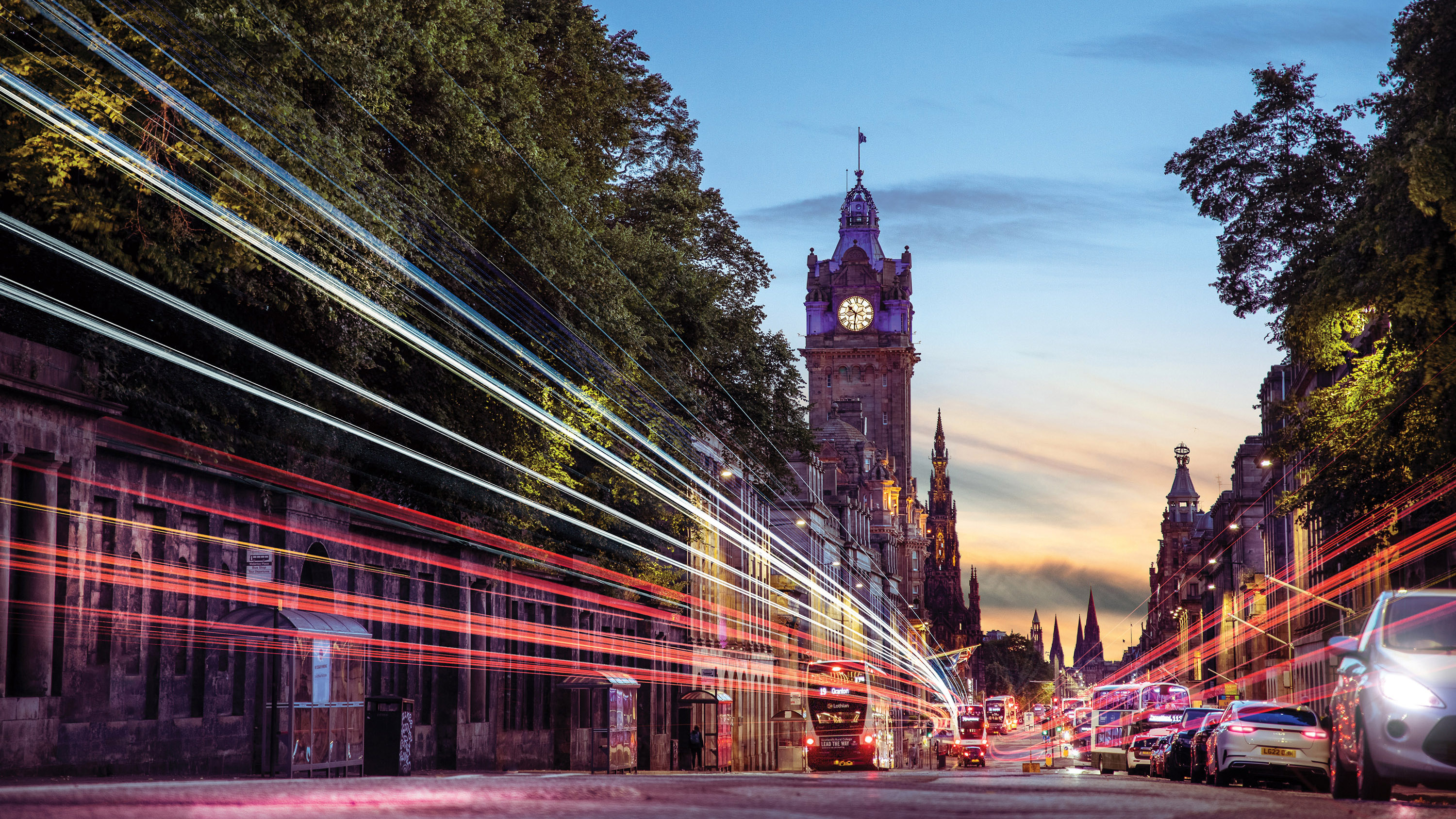 An evening image of Princes Street in Edinburgh, at sunset, with light trails from passing traffic