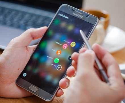 A man holding the Galaxy Note 5 and trying to use the S Pen